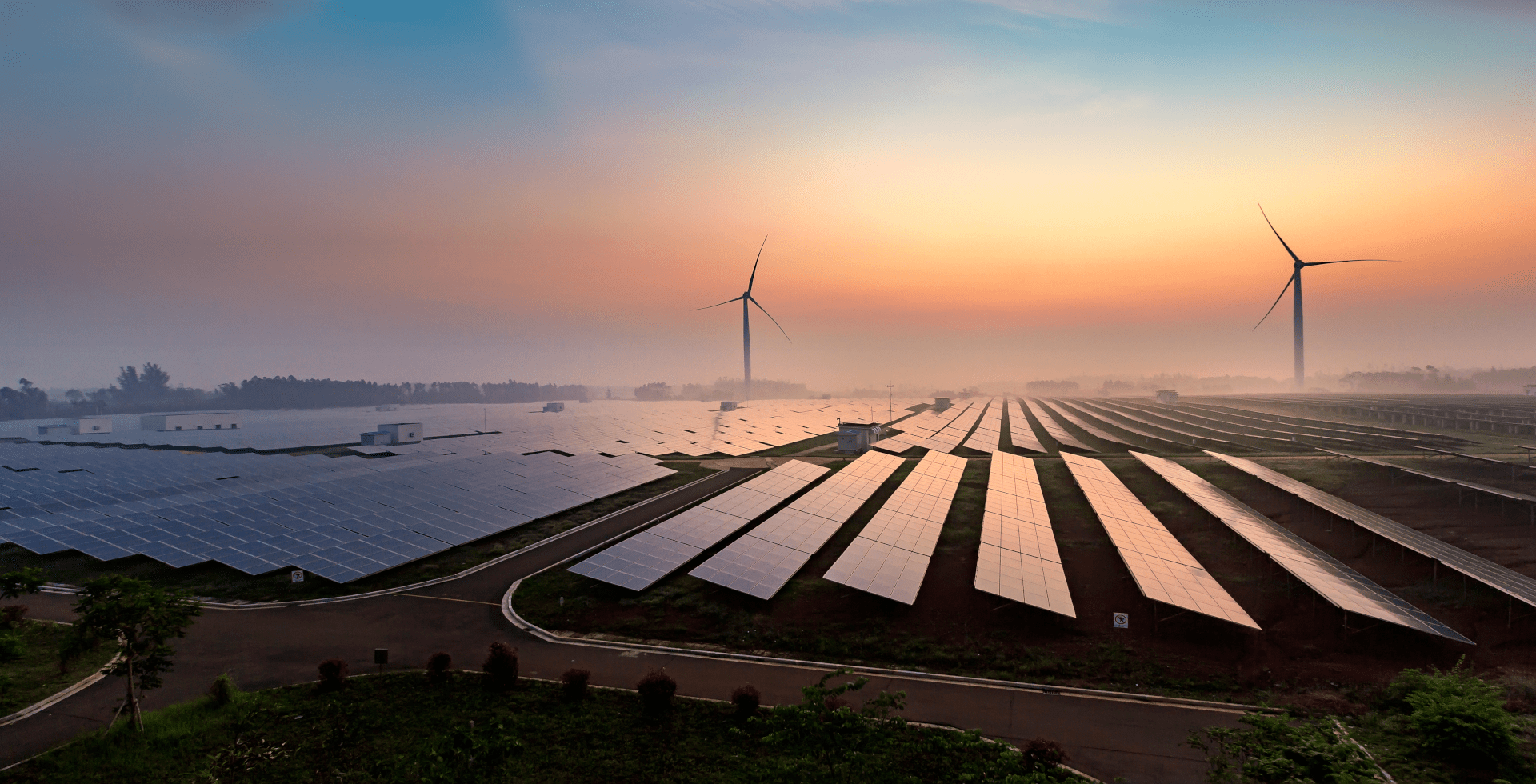 Solarzellen im Vordergrund, zwei Windräder im Hintergrund